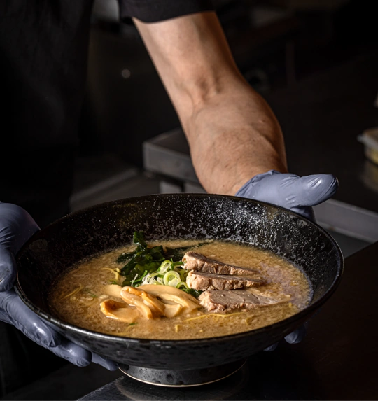 A bowl of ramen served by hand